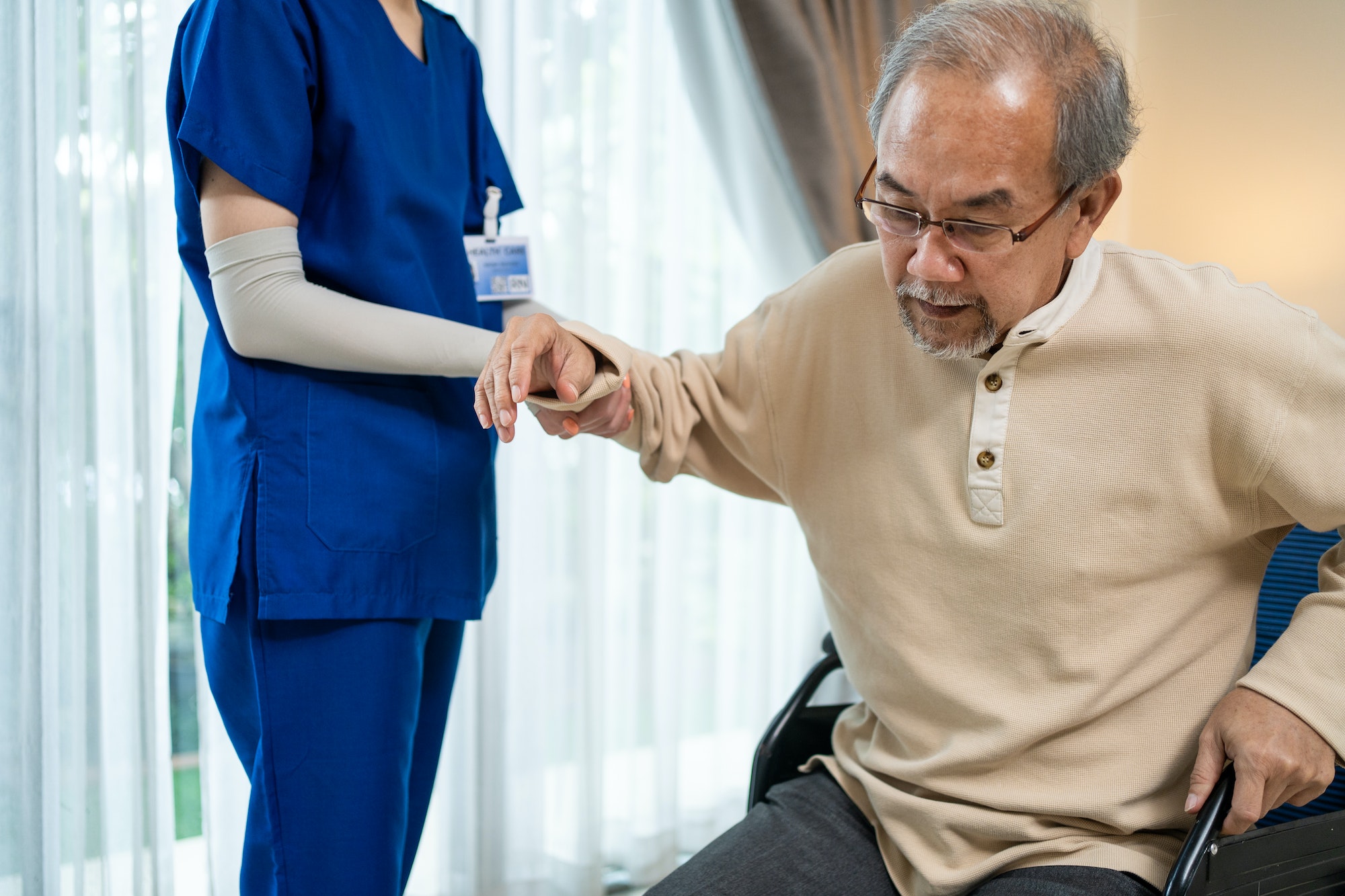 Asian Senior elderly disabled man patient walking slowly with walker at nursing home care.