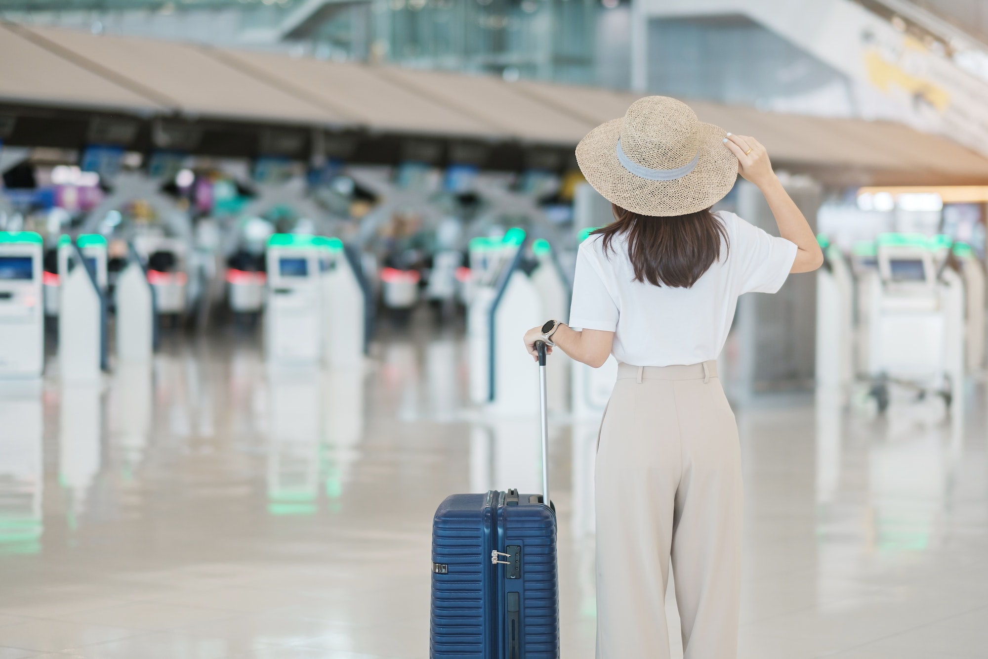 Young woman hand holding luggage handle before checking flight time in airport, Transport, insurance